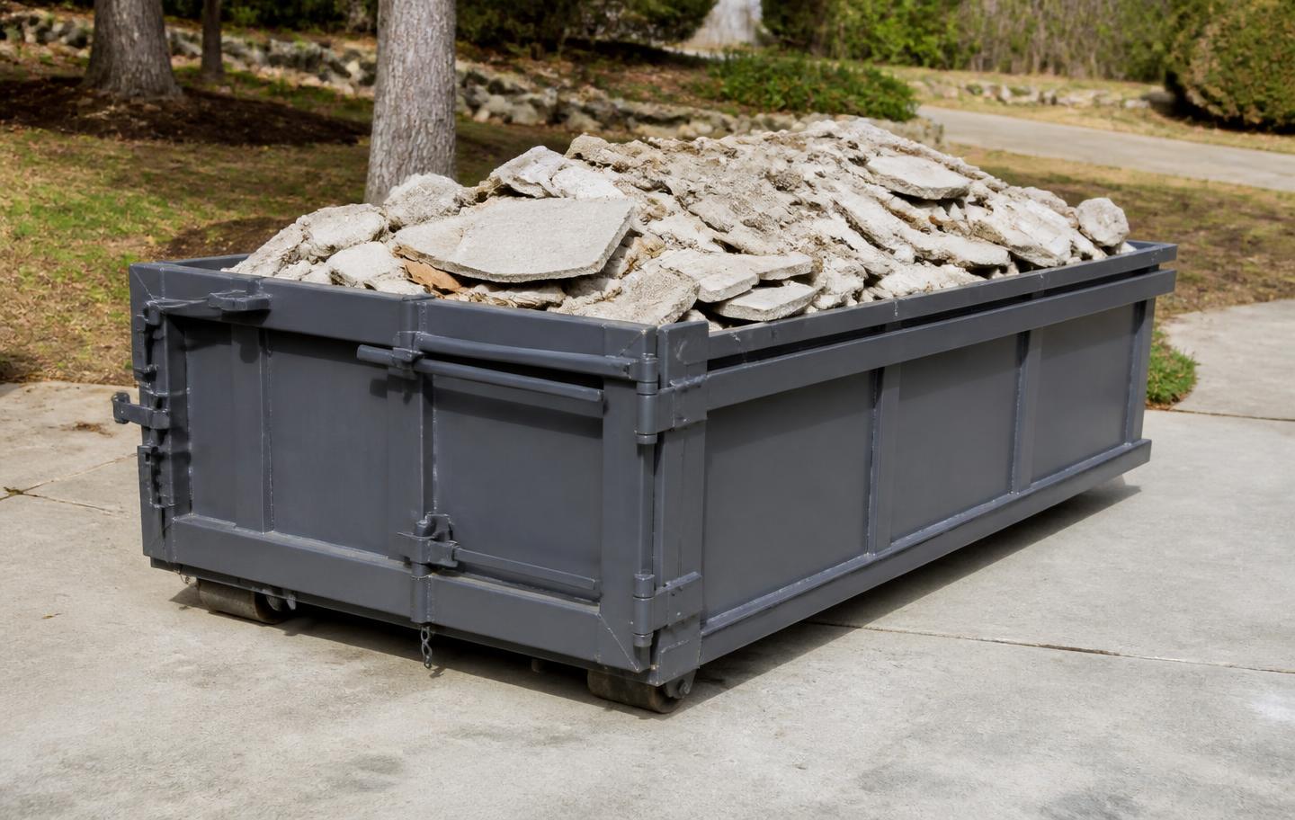 Compact 10-yard roll-off dumpster on a driveway loaded with broken concrete and tile