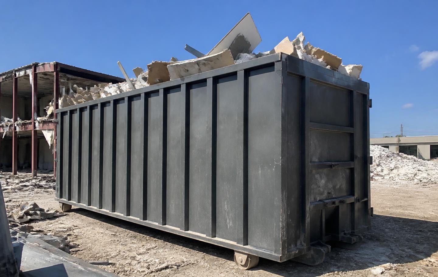 Large 40-yard roll-off dumpster filled with demolition debris at a commercial site